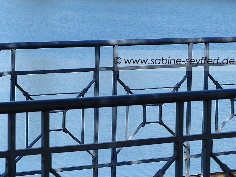 Geländer am See mit blauem Wasser